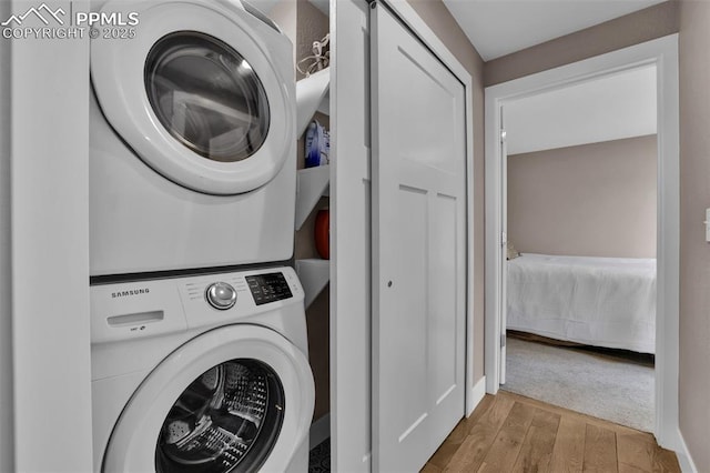 laundry room featuring laundry area, stacked washing maching and dryer, and wood finished floors
