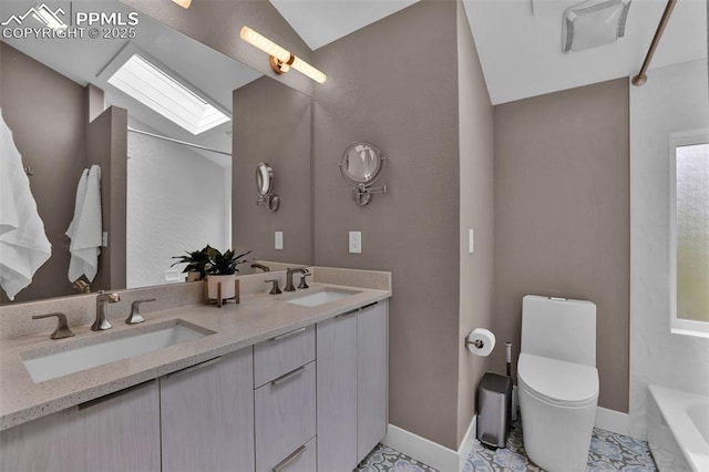 bathroom featuring a sink, baseboards, a skylight, and toilet