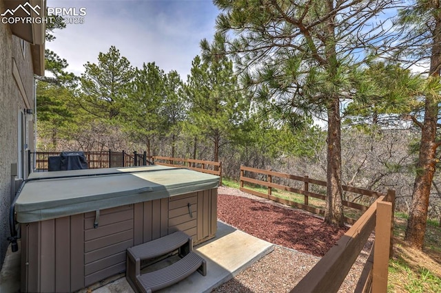 deck with a hot tub and fence