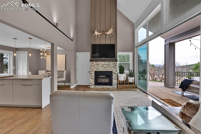 living room with high vaulted ceiling, a fireplace, light wood-style flooring, and a wealth of natural light