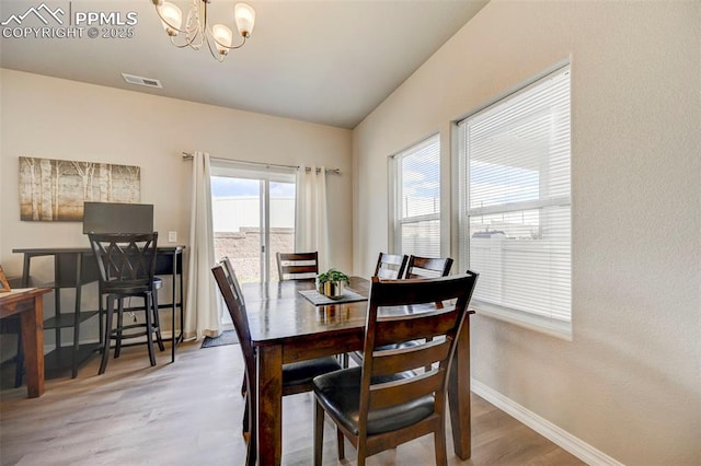dining room with wood finished floors, baseboards, a chandelier, and visible vents