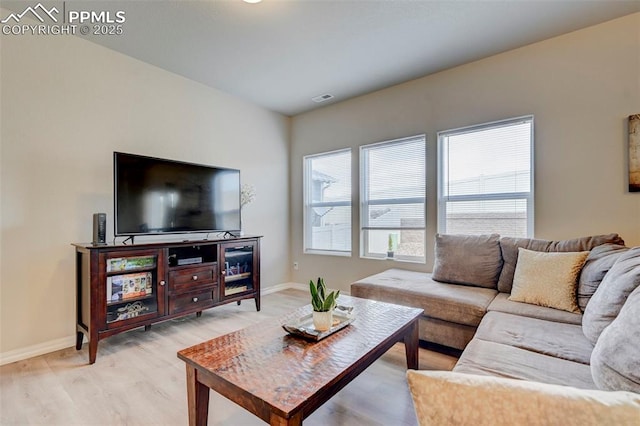 living area with baseboards, light wood-type flooring, and visible vents