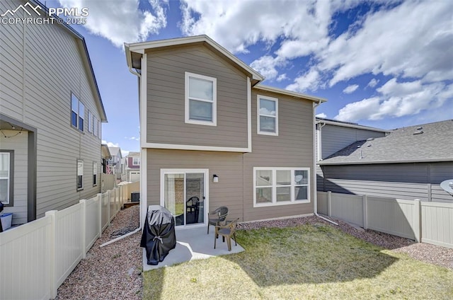 back of house with a fenced backyard, a yard, and a patio area