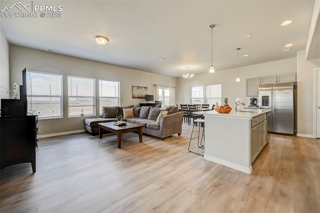 interior space featuring an inviting chandelier, stainless steel fridge, a breakfast bar, light wood finished floors, and light countertops