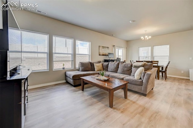 living room with visible vents, light wood finished floors, baseboards, and an inviting chandelier