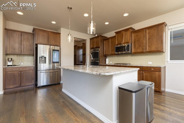 1849 Mud Hen Dr, Colorado Springs, CO 80921 - kitchen featuring appliances with stainless steel finishes, tasteful backsplash, dark wood finished floors, an island with sink, and recessed lighting