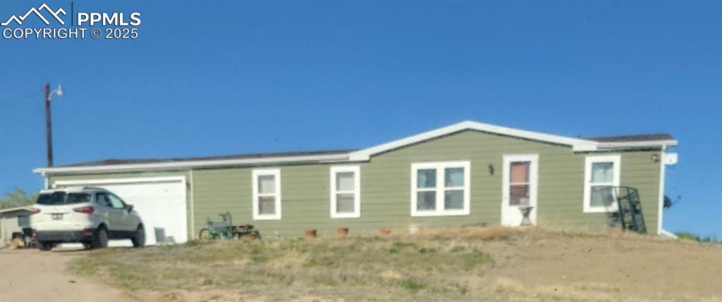 823 7th St, Hugo, CO 80821 - view of front of house featuring dirt driveway and a garage