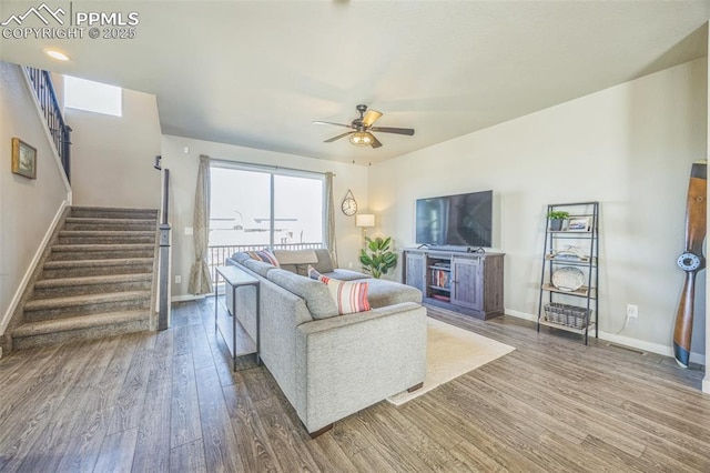 living room with wood finished floors, baseboards, stairway, and a ceiling fan