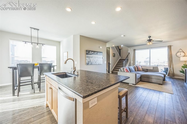 kitchen with a sink, dishwasher, light wood finished floors, a kitchen island with sink, and recessed lighting