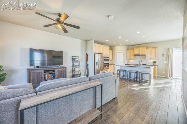 living area featuring wood finished floors, ceiling fan, and recessed lighting