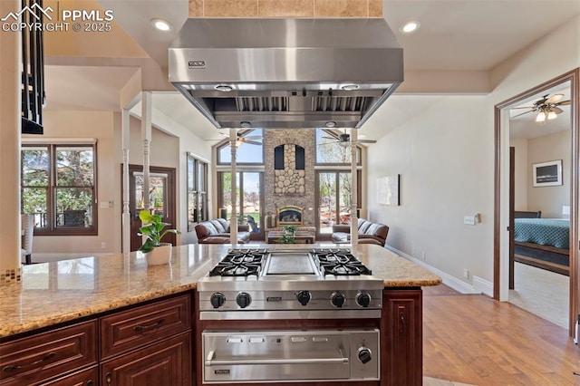 kitchen featuring a ceiling fan, ventilation hood, a warming drawer, and open floor plan