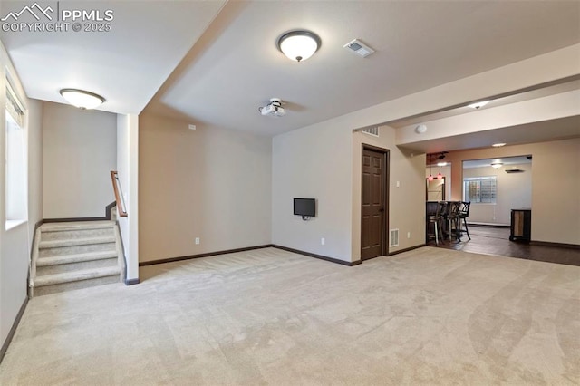 unfurnished living room with baseboards, carpet, stairs, and visible vents