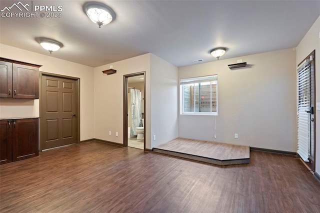 unfurnished room featuring baseboards, visible vents, and dark wood-type flooring