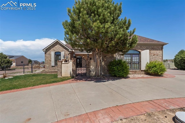 view of front of house featuring a gate, a fenced front yard, and brick siding