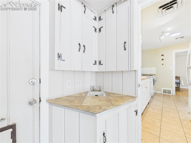 kitchen featuring white cabinets, visible vents, stove, and a sink