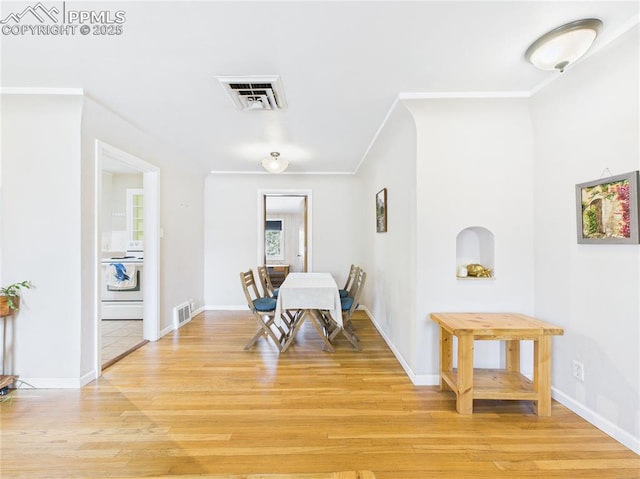 dining space with crown molding, baseboards, visible vents, and light wood-style flooring