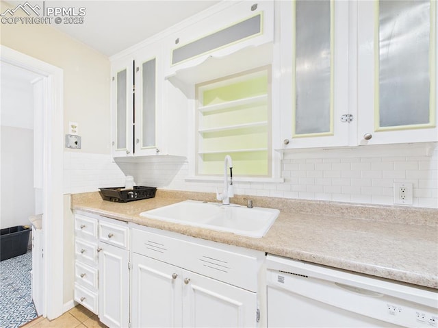kitchen featuring white dishwasher, light countertops, white cabinets, tasteful backsplash, and a sink