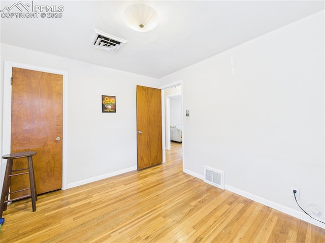 unfurnished room with baseboards, wood finished floors, and visible vents