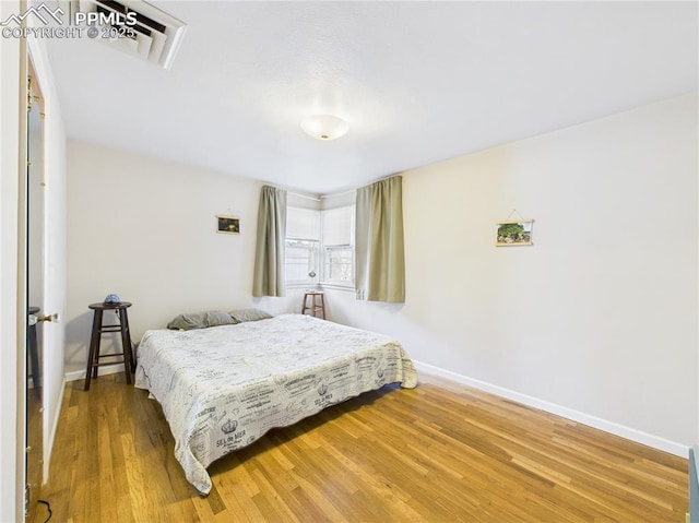 bedroom featuring baseboards, visible vents, and wood finished floors