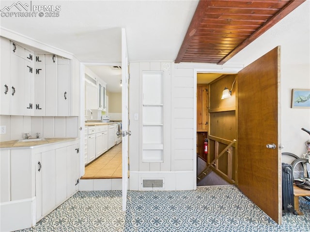 kitchen with visible vents, light countertops, white cabinetry, light tile patterned floors, and range