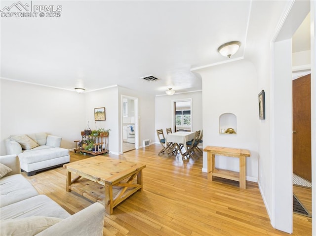 living room with baseboards, visible vents, and light wood finished floors