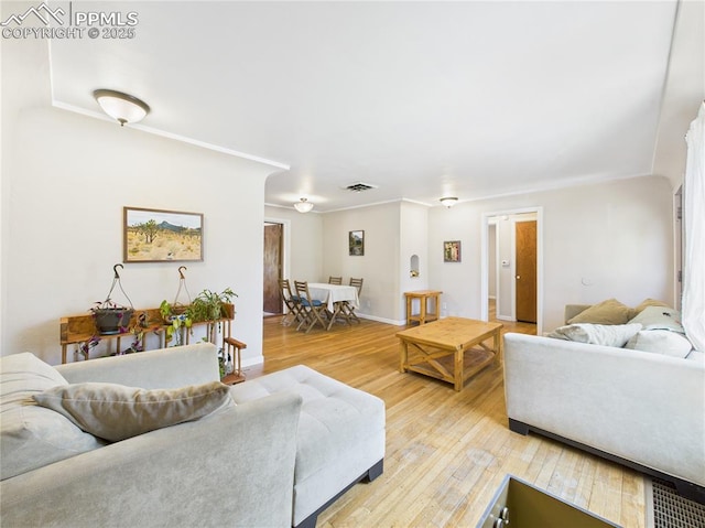 living room with visible vents, light wood-style flooring, and baseboards