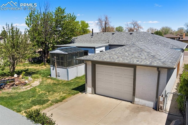 view of front of home featuring a front lawn, fence, concrete block siding, roof with shingles, and concrete driveway