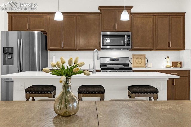 kitchen featuring appliances with stainless steel finishes, decorative light fixtures, and a kitchen bar