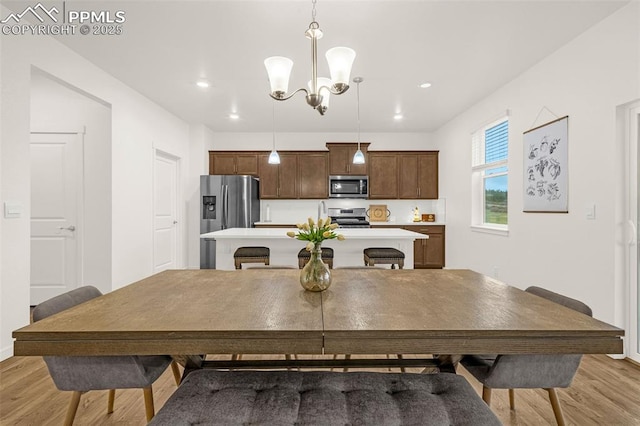 dining space with recessed lighting, an inviting chandelier, and light wood-style floors