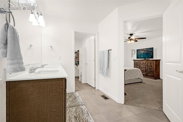 ensuite bathroom with a sink, tile patterned flooring, double vanity, a ceiling fan, and visible vents