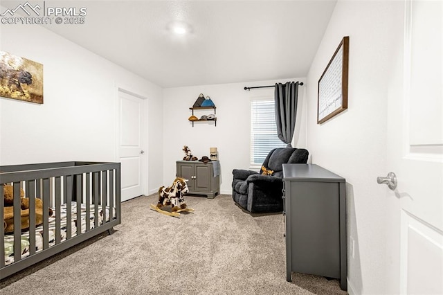 carpeted bedroom featuring baseboards and a crib