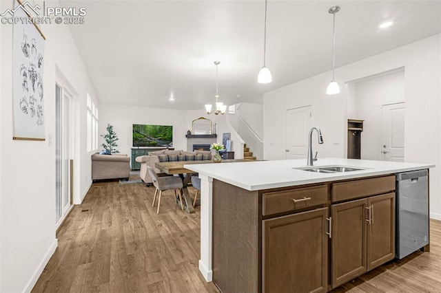 kitchen featuring light wood-style floors, a sink, dishwasher, and a lit fireplace