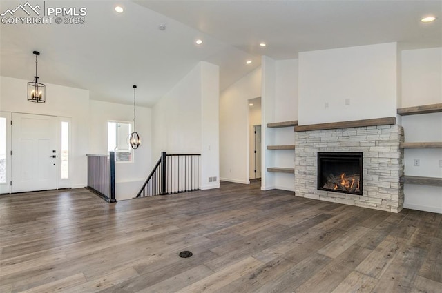 16990 Early Light Dr, Colorado Springs, CO 80908 - unfurnished living room with a fireplace, wood finished floors, high vaulted ceiling, an inviting chandelier, and recessed lighting