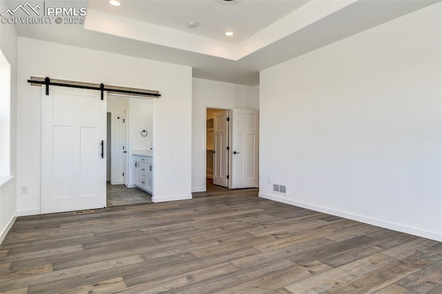 16990 Early Light Dr, Colorado Springs, CO 80908 - unfurnished bedroom featuring visible vents, wood finished floors, recessed lighting, a barn door, and a tray ceiling