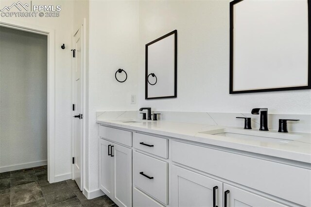 16990 Early Light Dr, Colorado Springs, CO 80908 - bathroom with baseboards, a sink, double vanity, and stone finish floor