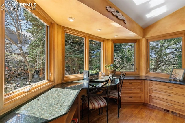 sunroom / solarium featuring vaulted ceiling, wood finished floors, and visible vents