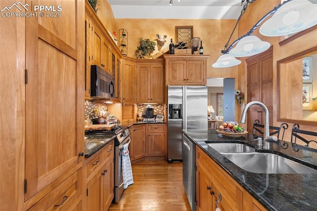 kitchen featuring a sink, brown cabinetry, stainless steel appliances, decorative backsplash, and light wood-type flooring