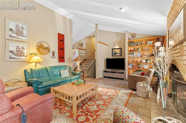 living room with stairway, stone finish floor, lofted ceiling, and a fireplace