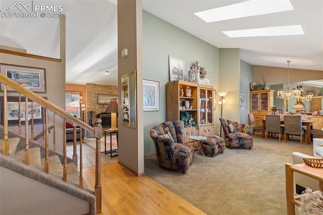 living room featuring a fireplace, a chandelier, wood finished floors, a skylight, and stairway