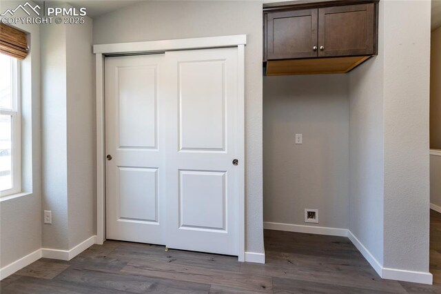 unfurnished bedroom featuring baseboards, dark wood-type flooring, and a closet