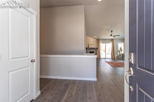 foyer with dark wood-style flooring, a ceiling fan, baseboards, and a fireplace
