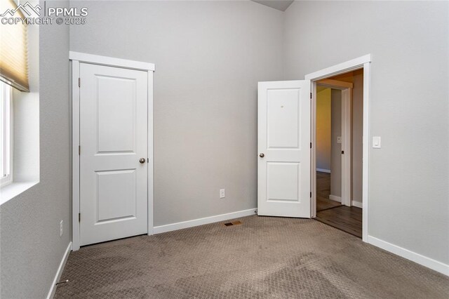unfurnished bedroom with carpet floors, baseboards, and visible vents