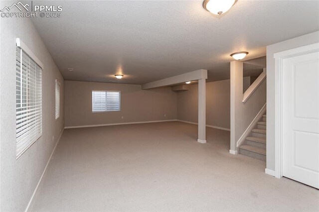 basement featuring baseboards, carpet flooring, stairs, and a textured ceiling