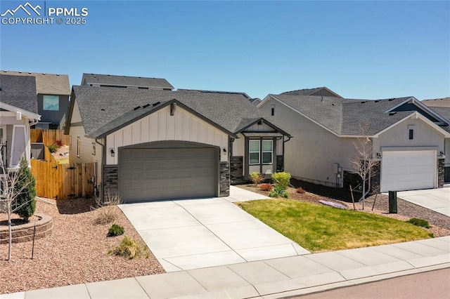 view of front of house with fence, roof with shingles, board and batten siding, an attached garage, and driveway