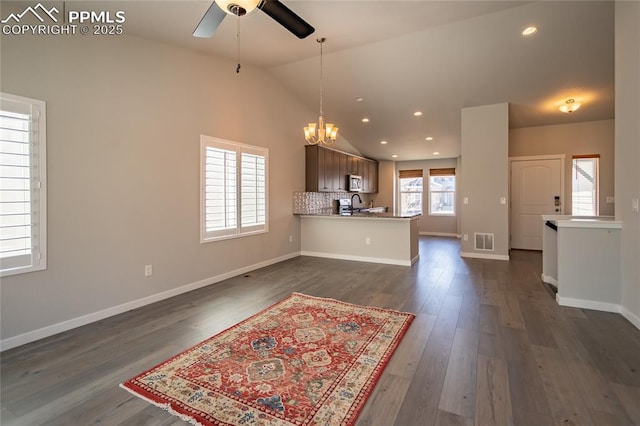 kitchen featuring visible vents, a sink, stainless steel microwave, ceiling fan with notable chandelier, and a peninsula