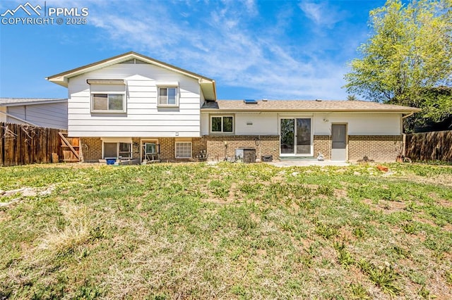back of house with brick siding, a fenced backyard, a lawn, and central AC