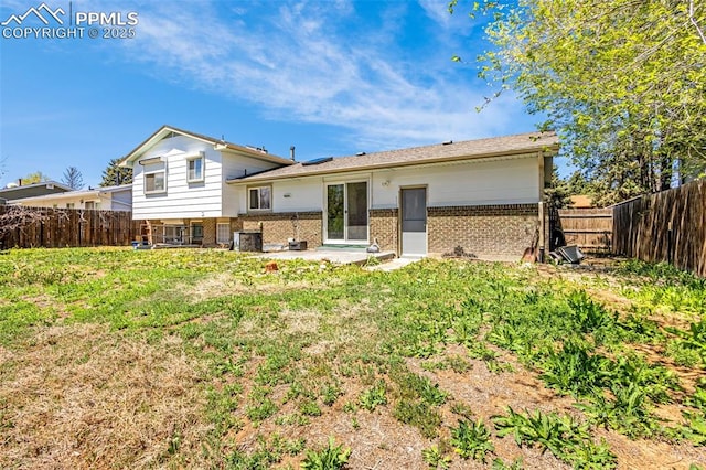 back of property with brick siding, a fenced backyard, central AC, and a patio