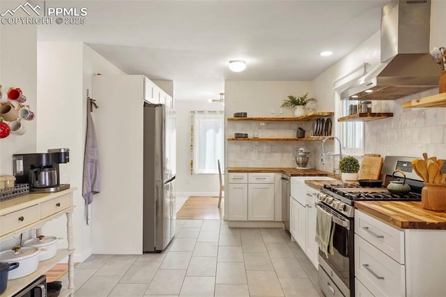 kitchen with exhaust hood, stainless steel appliances, open shelves, and butcher block counters