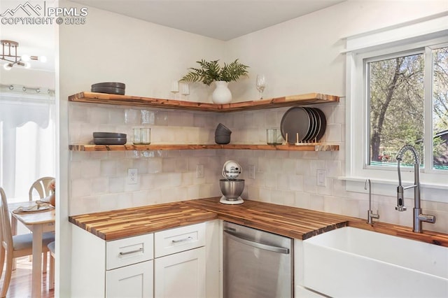 kitchen with stainless steel dishwasher, a sink, open shelves, and wooden counters