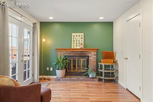living area with a fireplace, french doors, recessed lighting, baseboards, and wood finished floors